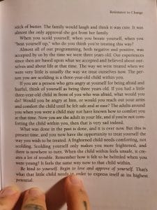 Sover Travel - A person holding an open book titled Resistance to Change, showing a page discussing childhood experiences, self-acceptance, fear, and compassion. The deep text encourages empathy towards ones inner child.
