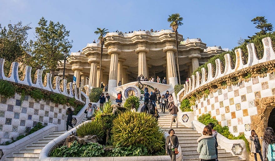**Alt Text:** Visitors explore the vibrant architecture and gardens of Park Güell in Barcelona. **Caption:** Discover the enchanting beauty of Park Güell, a perfect spot for mindful travel and relaxation. **Image Description:** A bustling scene at Park Güell, showcasing its unique architecture and lush greenery.