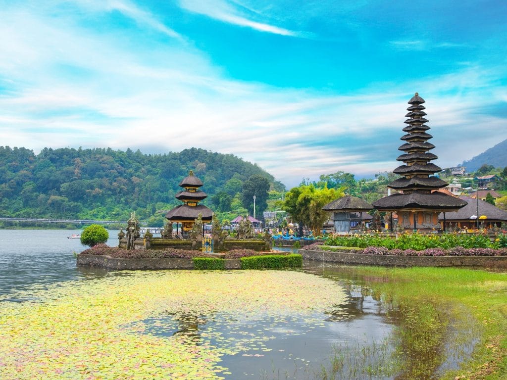 Sover Travel - Discover the scenic view of Pura Ulun Danu Bratan, one of Balis best destinations for sober travelers. This water temple, nestled by a calm lake adorned with lily pads, boasts multi-tiered pagodas set against lush green hills and a clear blue sky—adventures without hangover guaranteed.